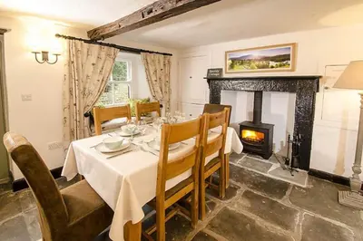 a dining room with a table and a fireplace at Speddy Cottage, Chapel Stile in Chapel Stile