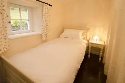 a small bedroom with a bed and a window at Speddy Cottage, Chapel Stile in Chapel Stile
