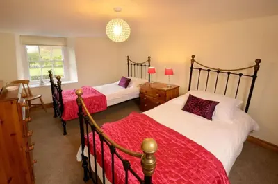 a bedroom with two beds with red and white sheets at Stickle Cottage, Great Langdale in Grasmere