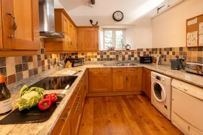 a kitchen with wooden cabinets and a sink with vegetables on the counter at Stickle Cottage, Great Langdale in Grasmere