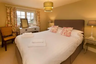 a bedroom with a large white bed with two towels at The Eltermere Old Barn, Elterwater in Elterwater