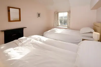 two beds in a room with white sheets at The Old White Lion, Chapel Stile in Chapel Stile