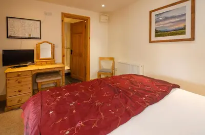 a bedroom with a bed and a desk with a television at The Stables, Elterwater in Elterwater