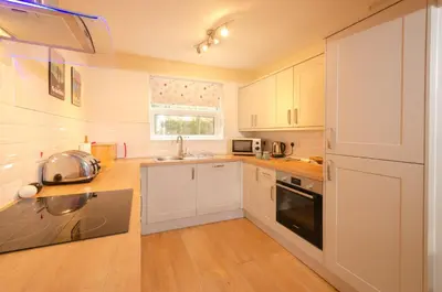 a kitchen with white cabinets and a sink at Underthrang, Chapel Stile in Chapel Stile
