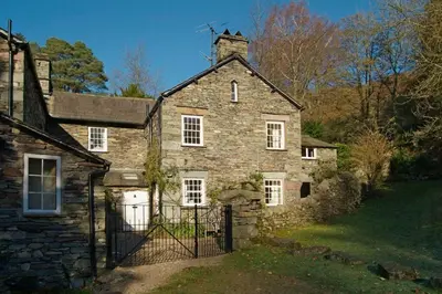 an old stone house with a gate in a yard at Woodland Crag Cottage, Grasmere in Grasmere