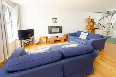 a living room with a blue couch and a tv at Jadians Nook, 16 Thrang Brow in Chapel Stile