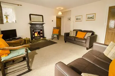 a living room with a couch and a fireplace at Juniper Grasmere - Juniper Cottage, Grasmere in Grasmere
