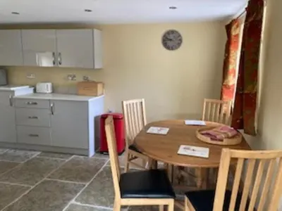 a kitchen with a wooden table and chairs in a room at Cottage at Inch Farm solitude beside the River in Longtown