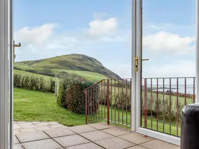 an open door with a view of a hill at Cairn-O-Mhor in Lendalfoot