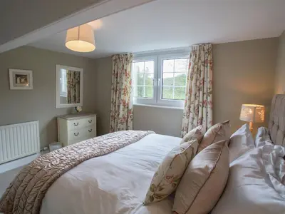 a bedroom with a large white bed and a window at Plumblands in Ambleside