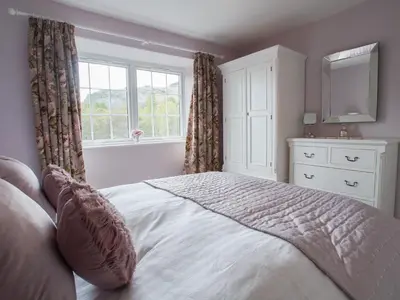 a bedroom with a bed with a dresser and a mirror at Plumblands in Ambleside