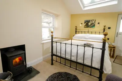 a bedroom with a bed and a wood stove at Anns Cottage, Chapel Stile in Chapel Stile