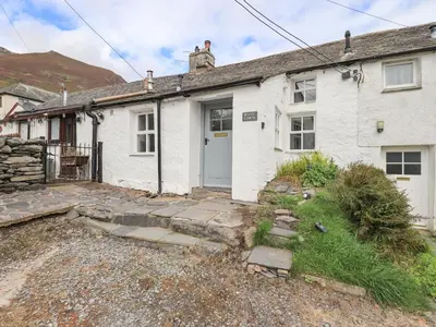 a white house with a door in a yard at Blease Garth in Threlkeld