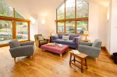a living room with a couch and chairs and windows at Heron Place, Great Langdale in Ambleside