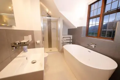 a white bathroom with a tub and a toilet at Heron Place, Great Langdale in Ambleside