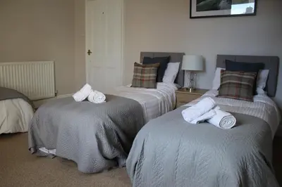 two beds with towels on them in a room at Carvetii - Quentin House - Near Hospital, max 7 ppl in Carlisle