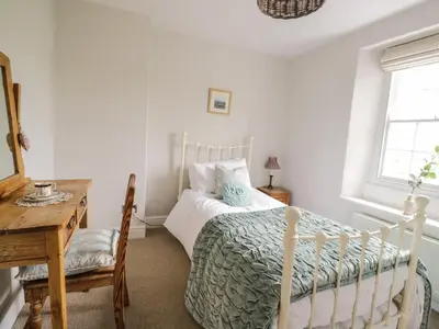 a bedroom with a bed and a table and a window at Beckside Cottage in Welton