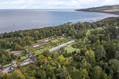 an aerial view of a castle on a hill next to a lake at Brewhouse Flat - Culzean Castle in Maybole