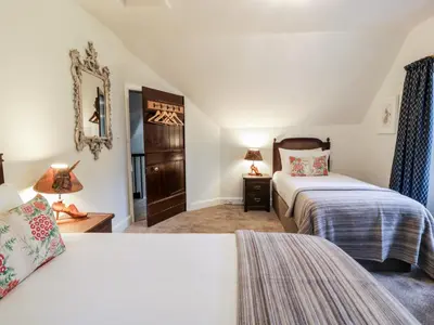 a bedroom with two beds and a mirror at Gate Lodge - Threave Estate in Castle Douglas