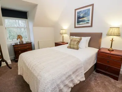 a bedroom with a white bed and two night stands at Gate Lodge - Threave Estate in Castle Douglas