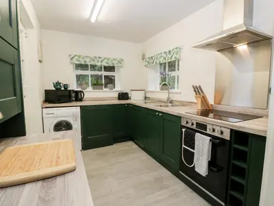 a kitchen with green cabinets and a sink at Gate Lodge - Threave Estate in Castle Douglas