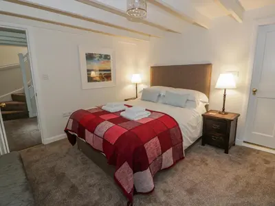 a bedroom with a bed with a red and white blanket at Blue Door - Kirkcudbright in Kirkcudbright