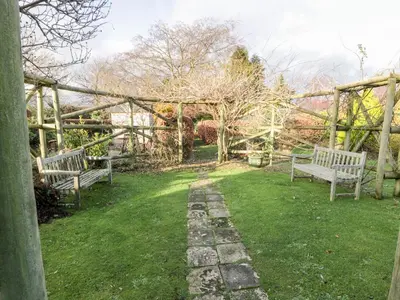 two benches sitting in the grass in a garden at Blue Door - Kirkcudbright in Kirkcudbright