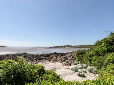a pathway leading to a beach with a body of water at Port Donnel Cottage in Dalbeattie