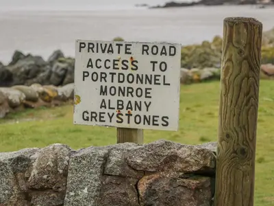 a sign on top of a stone wall at Port Donnel Cottage in Dalbeattie