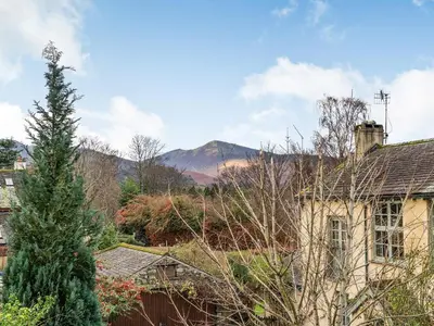 an old house with a mountain in the background at The Plosh in Keswick