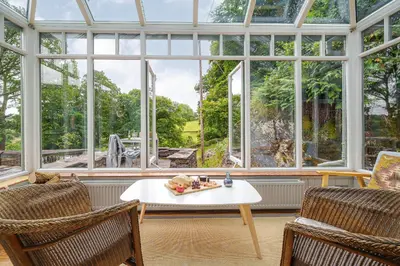 a conservatory with a table and two chairs and a window at The Stable At Oakbank in Elterwater