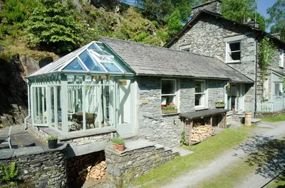 an old stone house with a greenhouse on it at The Stable At Oakbank in Elterwater