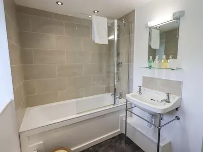 a bathroom with a tub and a sink and a shower at Yew Tree Cottage Borrowdale in Rosthwaite