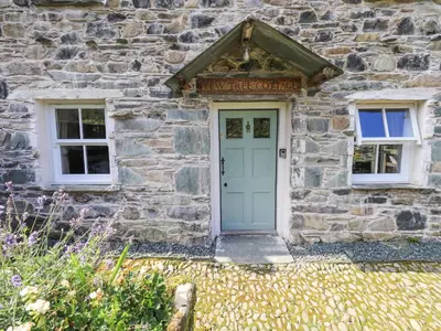 a stone house with a blue door and two windows at Yew Tree Cottage Borrowdale in Rosthwaite