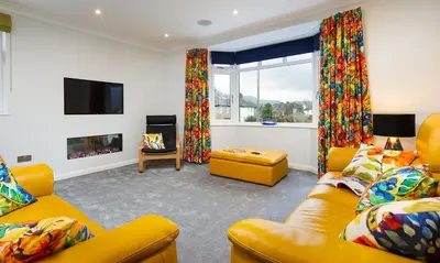 a living room with yellow furniture and a fireplace at Fell View in Keswick