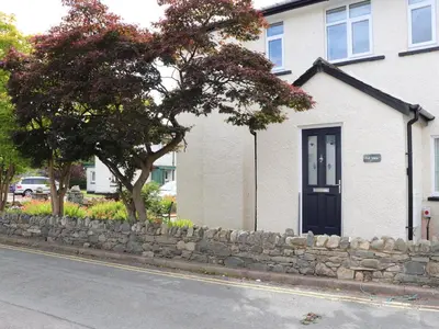 a house with a stone retaining wall and a tree at Fell View in Keswick