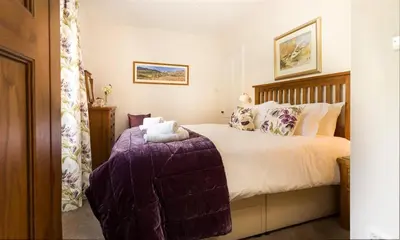 a bedroom with a bed with a purple blanket at Oxen Fell Cottage in Little Langdale
