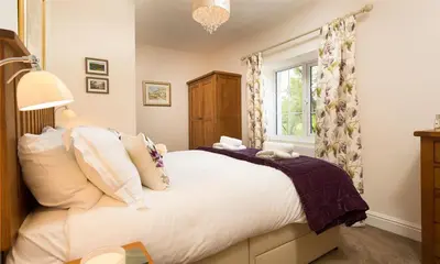 a bedroom with a large white bed and a window at Oxen Fell Cottage in Little Langdale