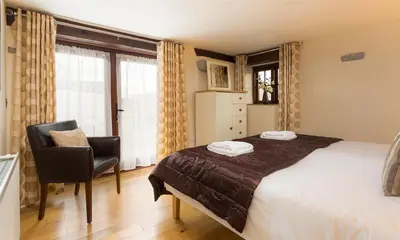 a bedroom with a bed and a chair and a window at Nest Barn in Keswick