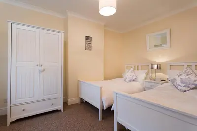 a bedroom with two beds and a closet at Noble Cottage in Keswick