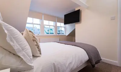 a bedroom with a bed with a television on the wall at Noble Cottage in Keswick