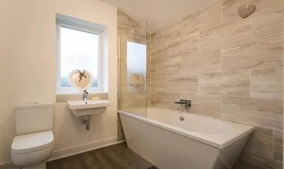 a bathroom with a tub and a toilet and a sink at Noble Cottage in Keswick