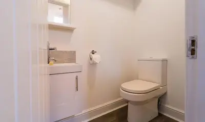 a white bathroom with a toilet and a sink at Noble Cottage in Keswick