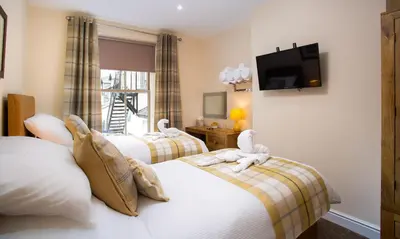 two beds with stuffed animals on them in a hotel room at Dovedale in Keswick