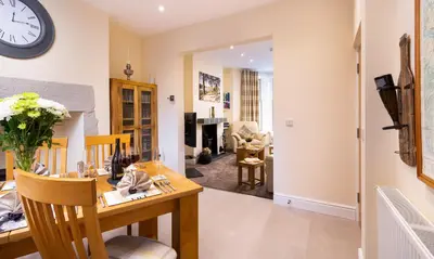 a living room with a table and a clock on the wall at Dovedale in Keswick