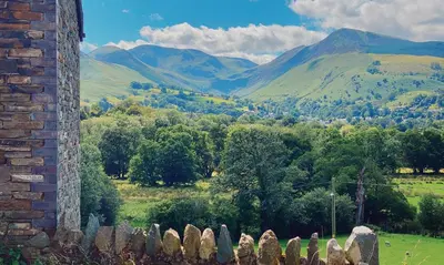 a field with a fence and mountains in the background at One The Howe in Portinscale
