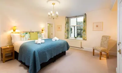 a bedroom with a bed and a chair and a window at One The Howe in Portinscale