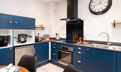 a kitchen with blue cabinets and a clock on the wall at Sunnybank Cottage in Keswick