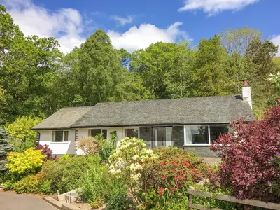 a house with a garden and trees at Merlestead in Applethwaite