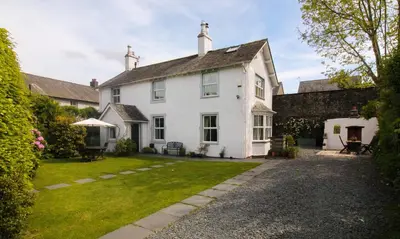 a white house with a yard in front of it at Crow Cottage in Keswick